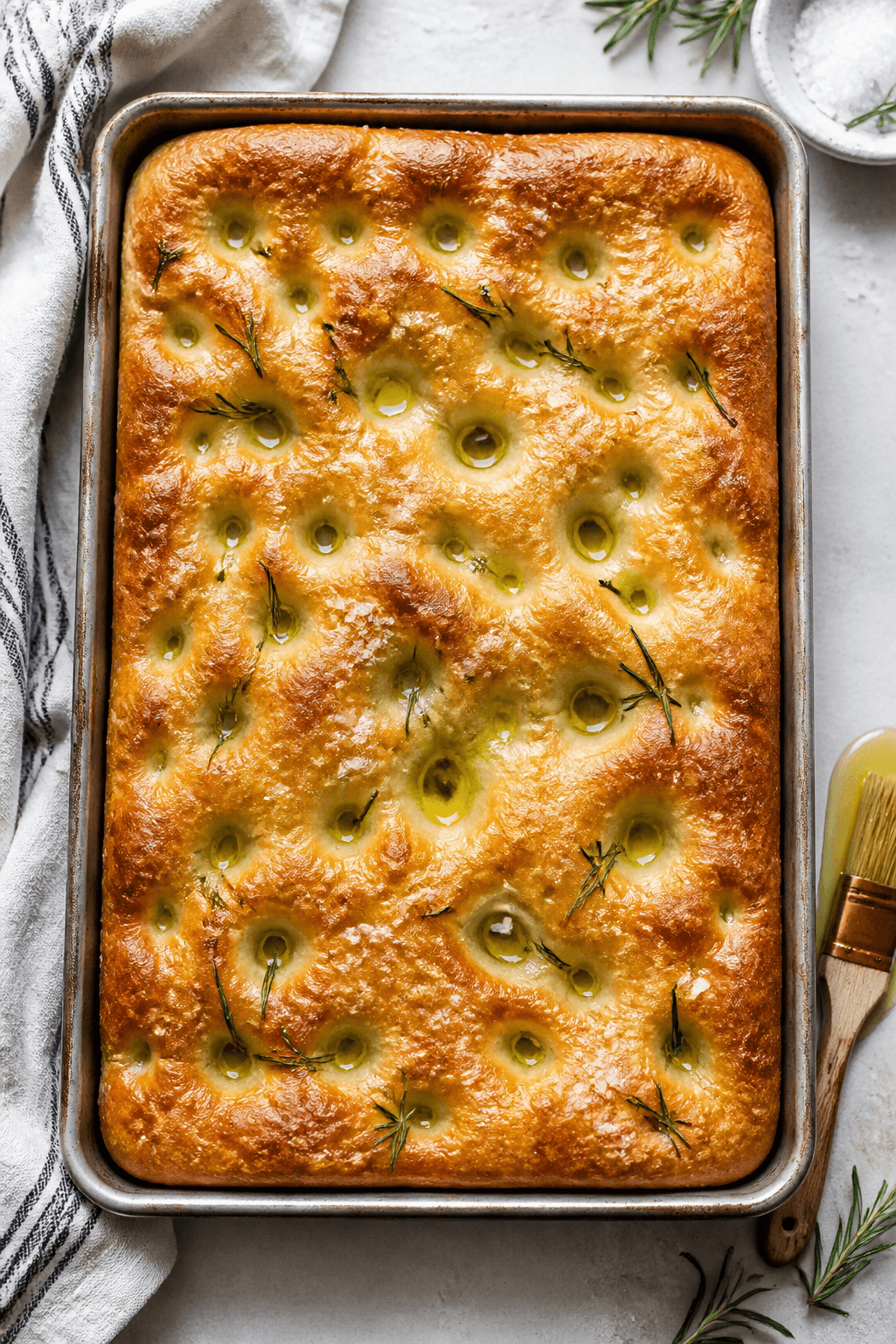 Overhead shot of freshly baked focaccia in a 9x13-inch pan just out of the oven, golden surface with
