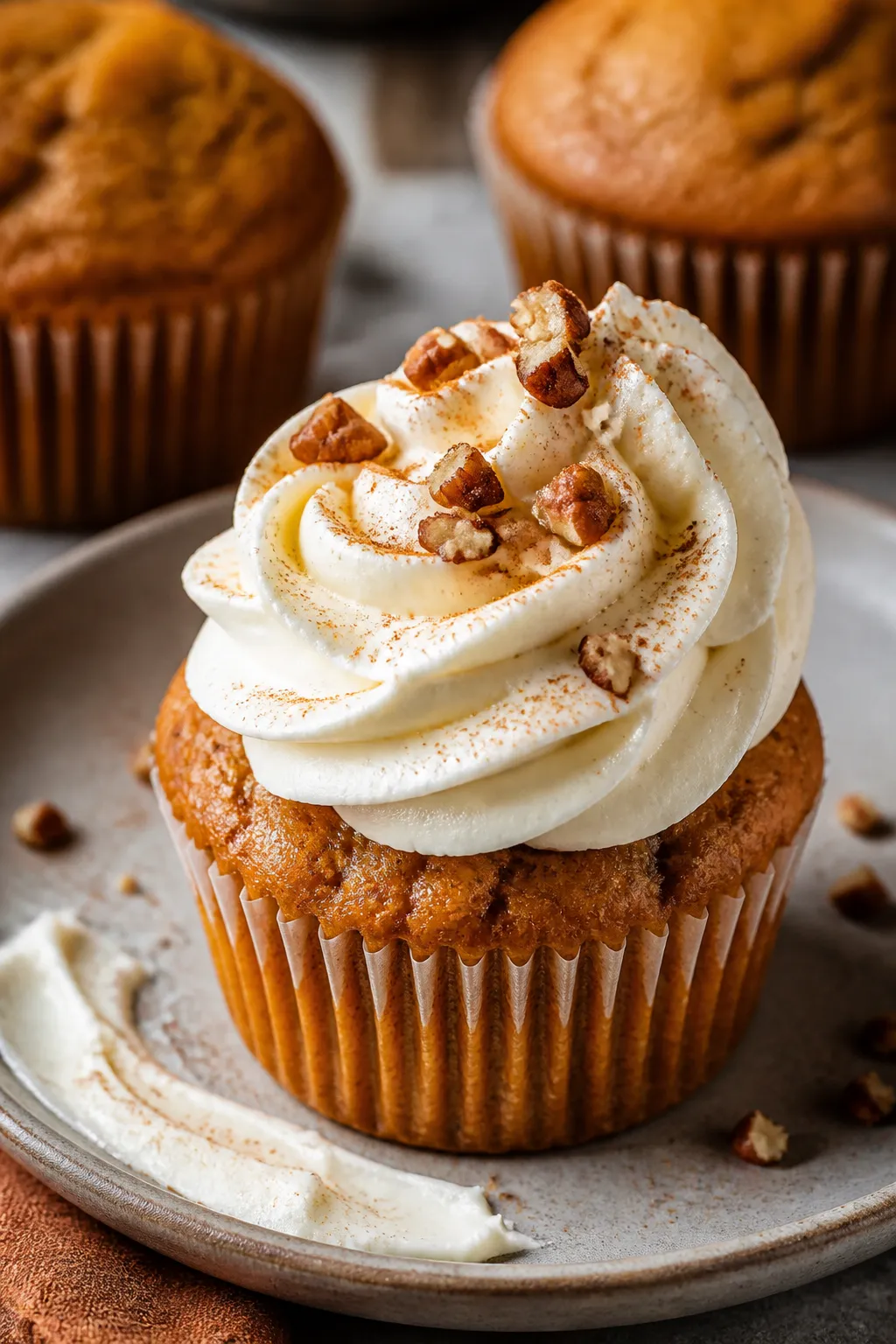 Close-up detail of a frosted pumpkin muffin on a matte ceramic plate, silky cream cheese frosting pi