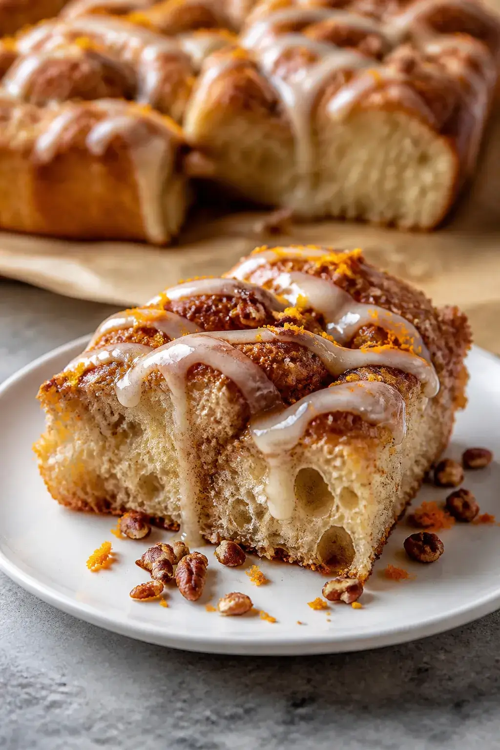Close-up detail of a pulled-apart square of sourdough cinnamon roll focaccia on a matte white plate,