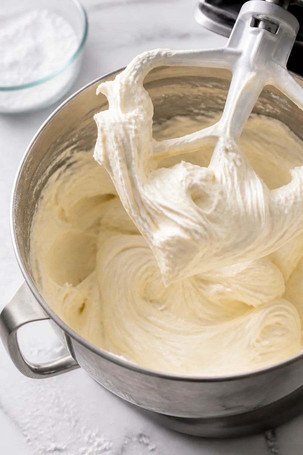 Close-up detail shot: A stand mixer bowl filled with freshly whipped vanilla buttercream at peak flu