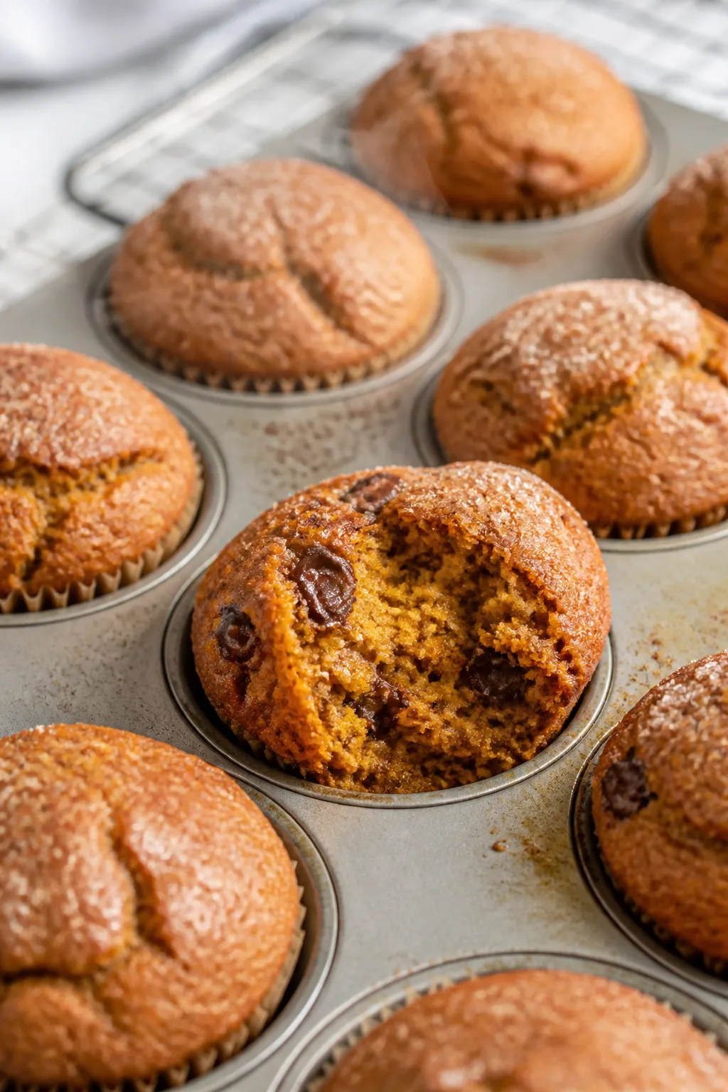 Close-up detail shot: freshly baked pumpkin banana muffins just out of the oven in a lined 12-cup mu