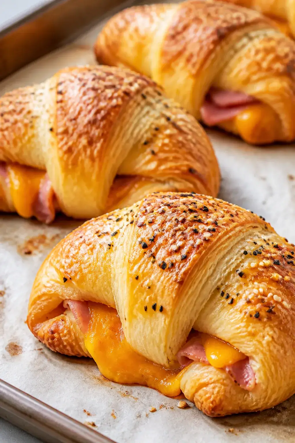 Close-up detail shot of freshly baked ham and cheese crescent rolls just out of the oven: golden-bro