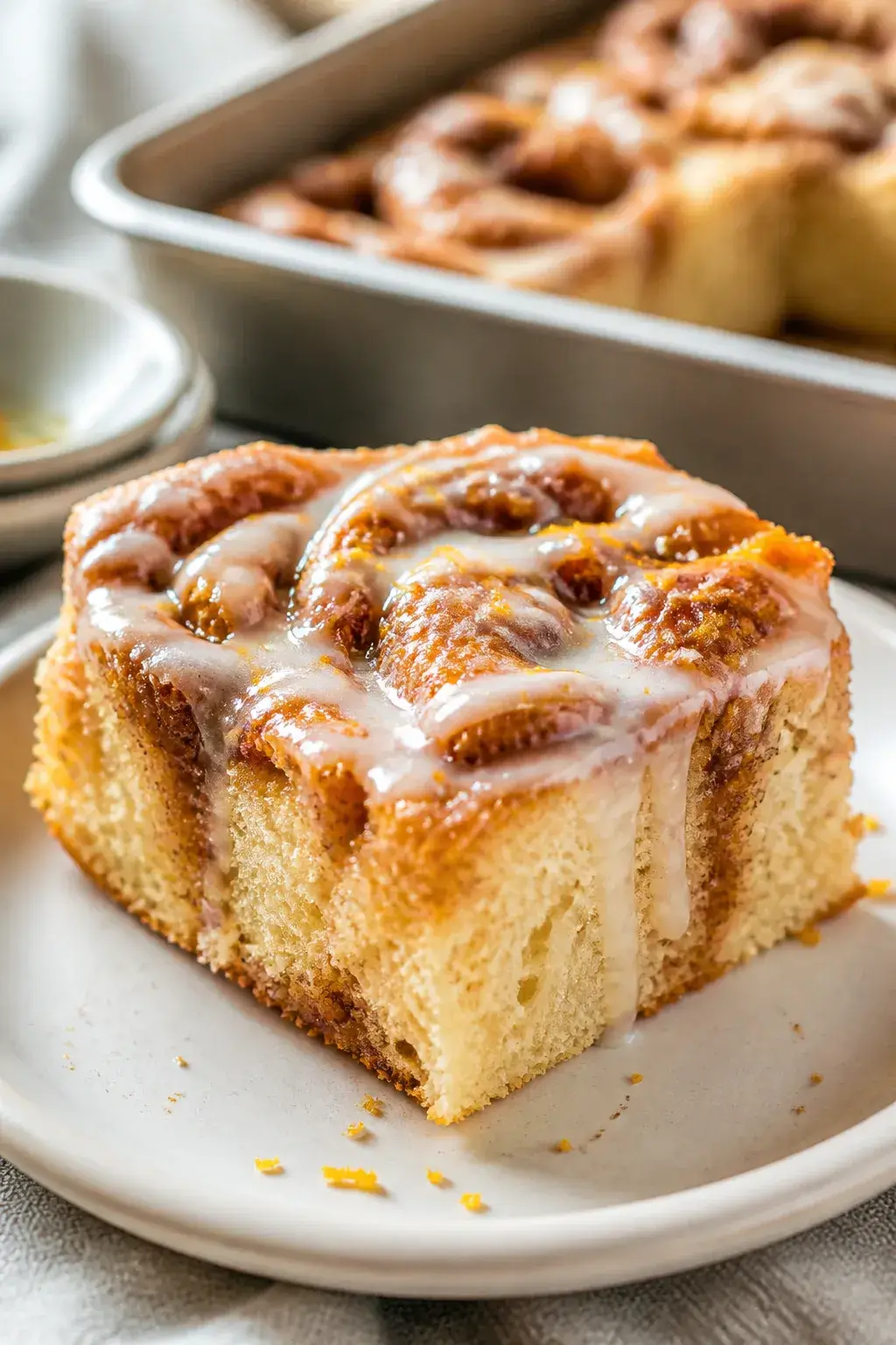 Close-up, three-quarter angle of a sliced square of cinnamon roll focaccia on a matte white plate: p
