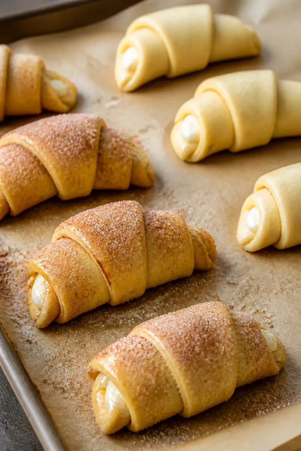 Cooking process close-up: Crescent roll triangles on a parchment-lined baking sheet, already filled