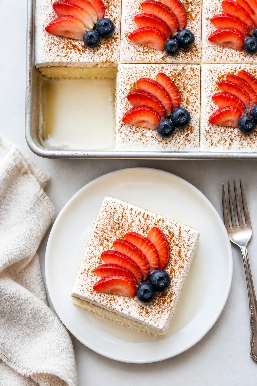 Final dish overhead: Chilled tres leches cake sliced and served cold, topped with a billowy layer of