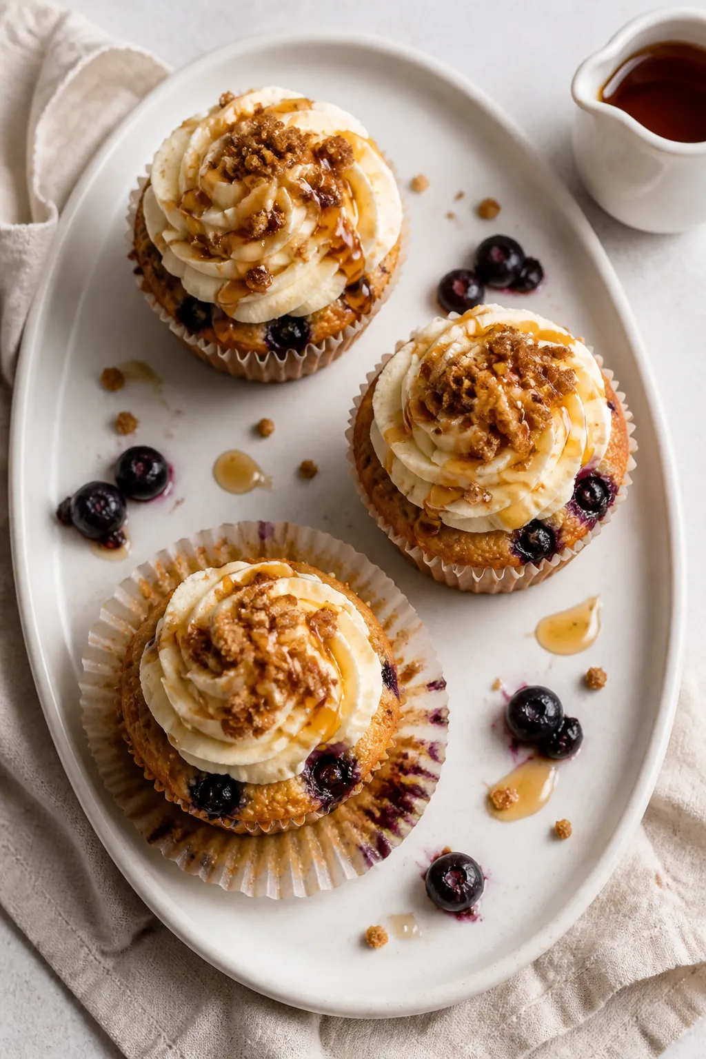 Overhead final presentation of a trio of frosted Blueberry French Toast Cupcakes on a white stonewar