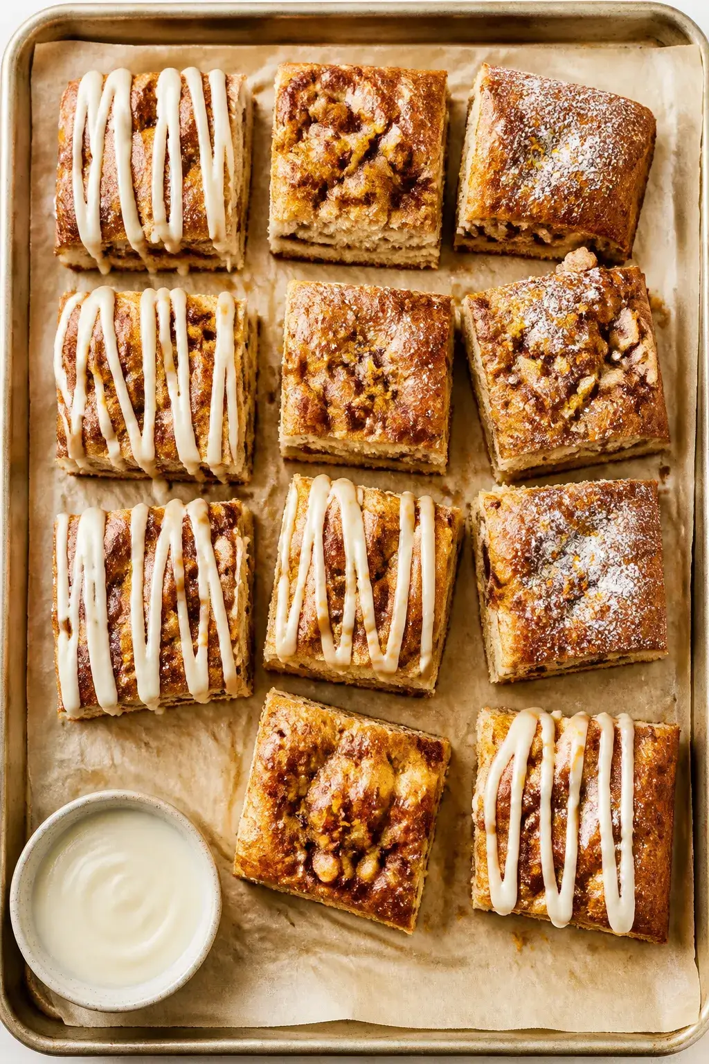 Overhead final presentation: Sliced squares of cinnamon roll focaccia on a parchment-lined sheet pan