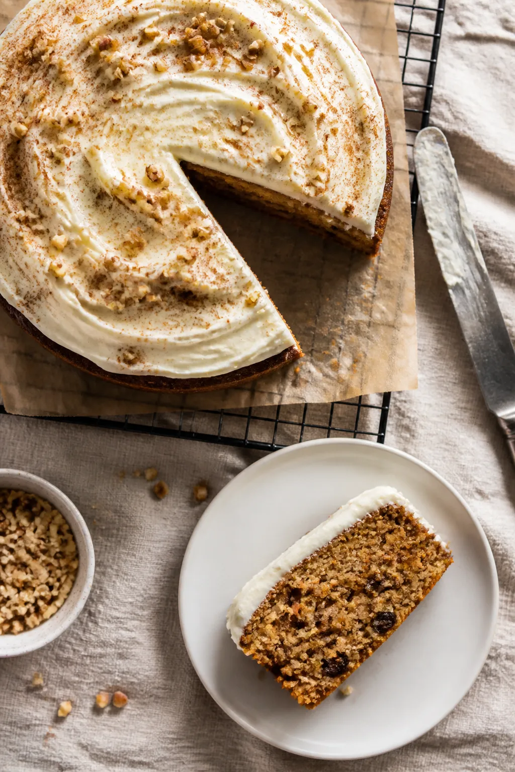 Overhead shot of a freshly frosted gluten free vegan carrot cake on a parchment-lined cooling rack,