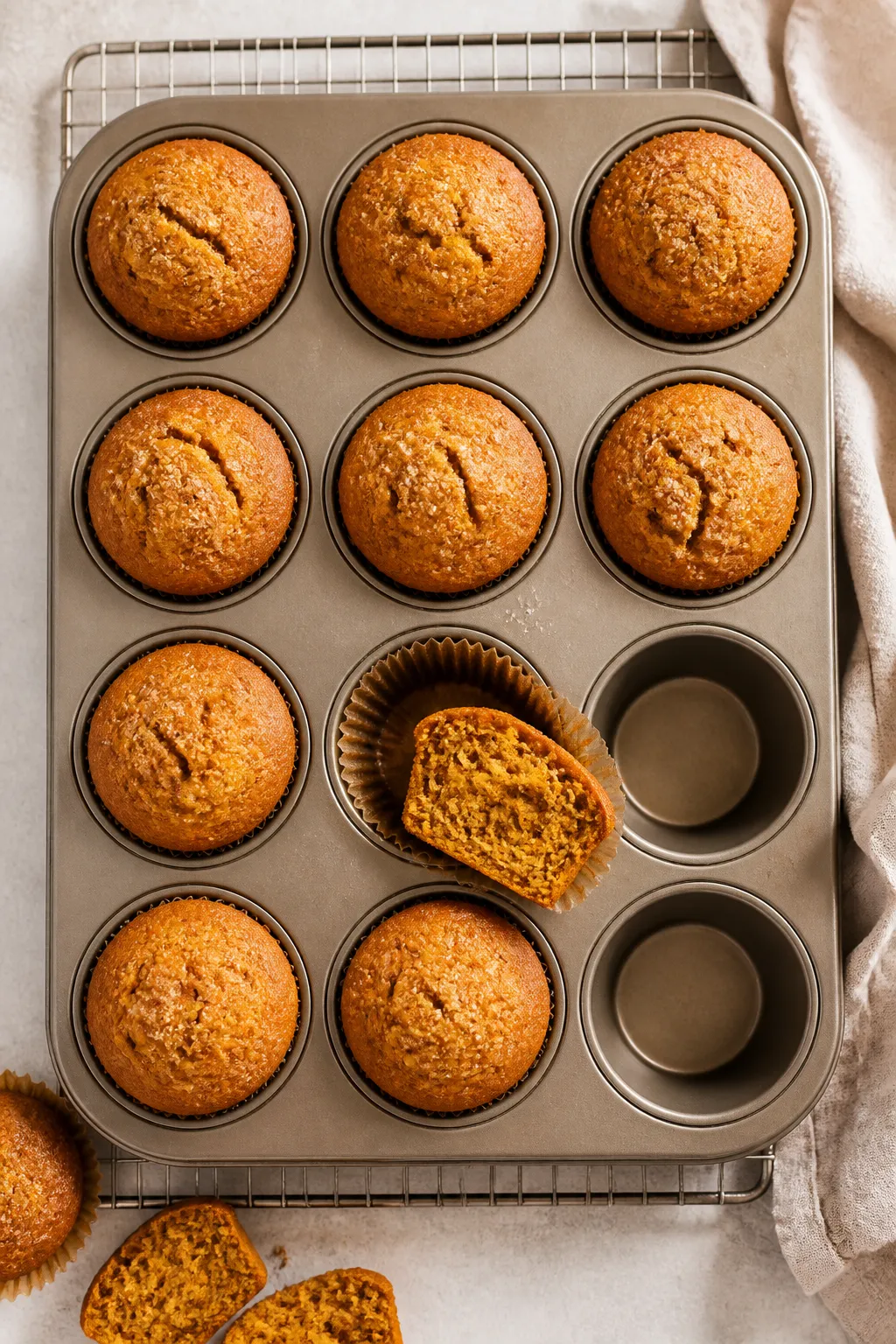 Overhead shot of freshly baked gluten free pumpkin muffins cooling in a 12-cup muffin tin on a wire