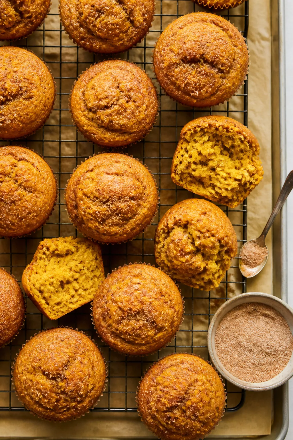 Overhead shot of freshly baked pumpkin muffins cooling on a wire rack, golden domed tops with a ligh