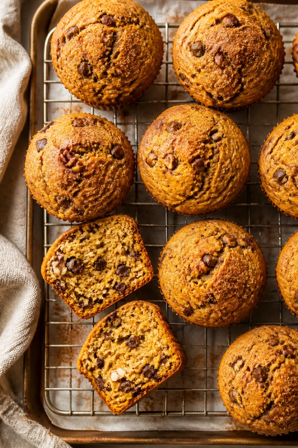 Overhead shot of freshly baked pumpkin muffins cooling on a wire rack, golden-brown domed tops with 