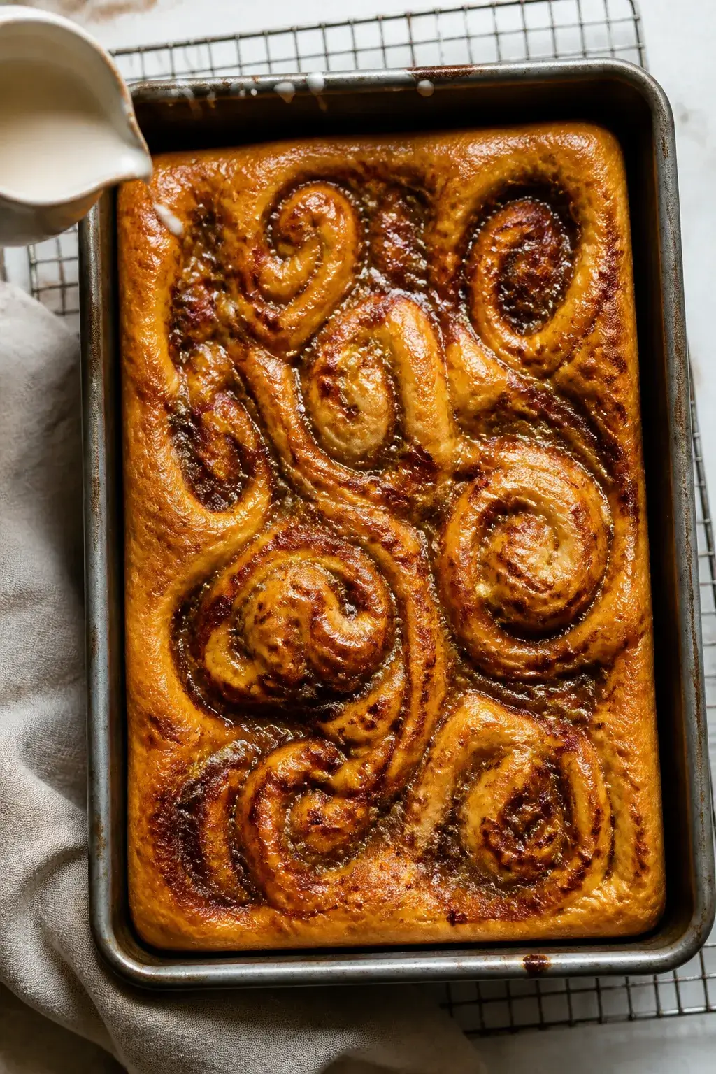 Overhead shot of freshly baked sourdough cinnamon roll focaccia in a generously oiled 9x13 metal pan